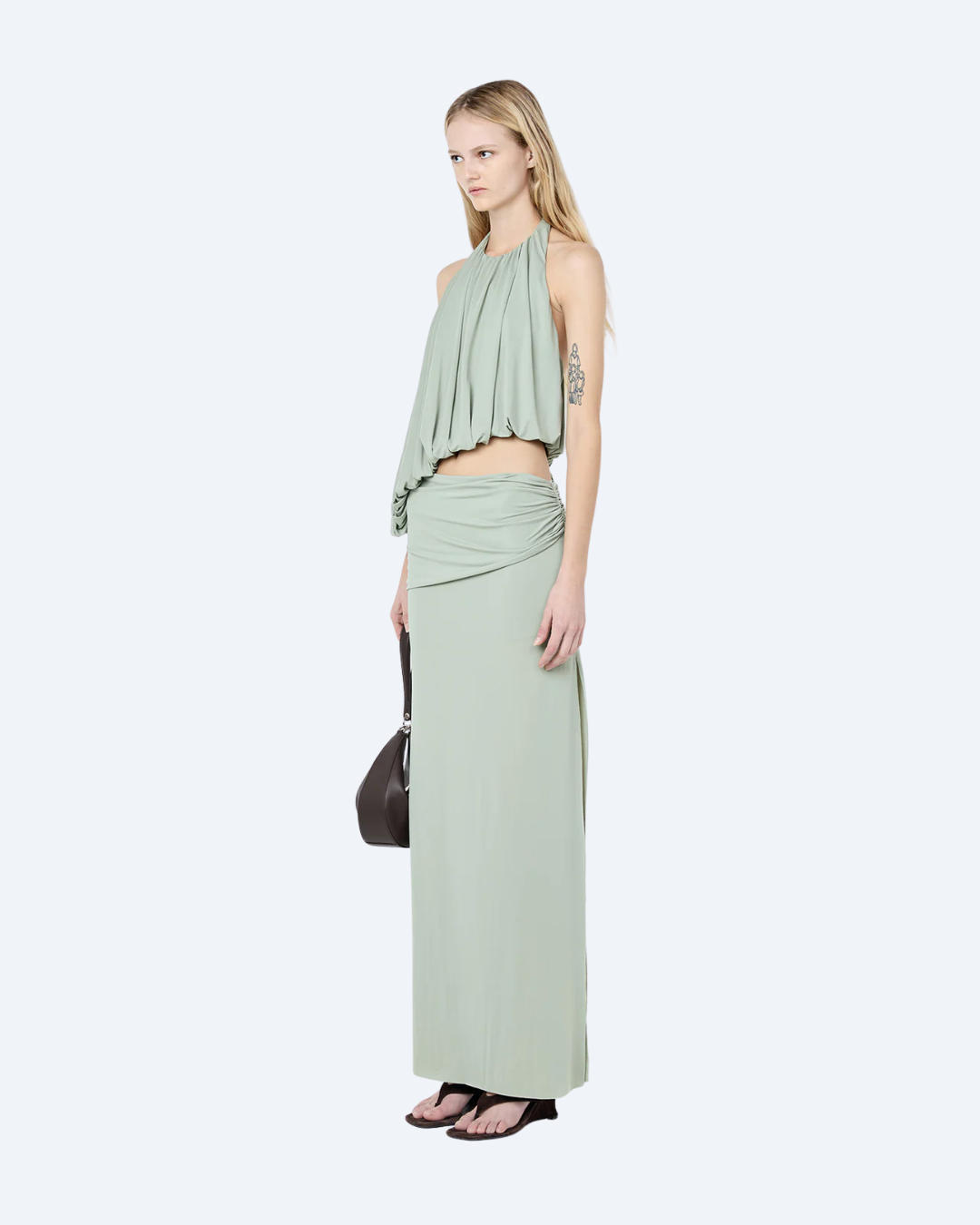 Woman wearing a pistachio Bec & Bridge Cadence Racer backless, maxi dress, angled view, on a white background