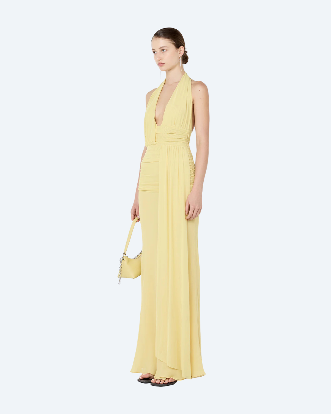 Woman wearing a yellow Bec & Bridge Cassis Drape backless, maxi dress, angled view, on a white background