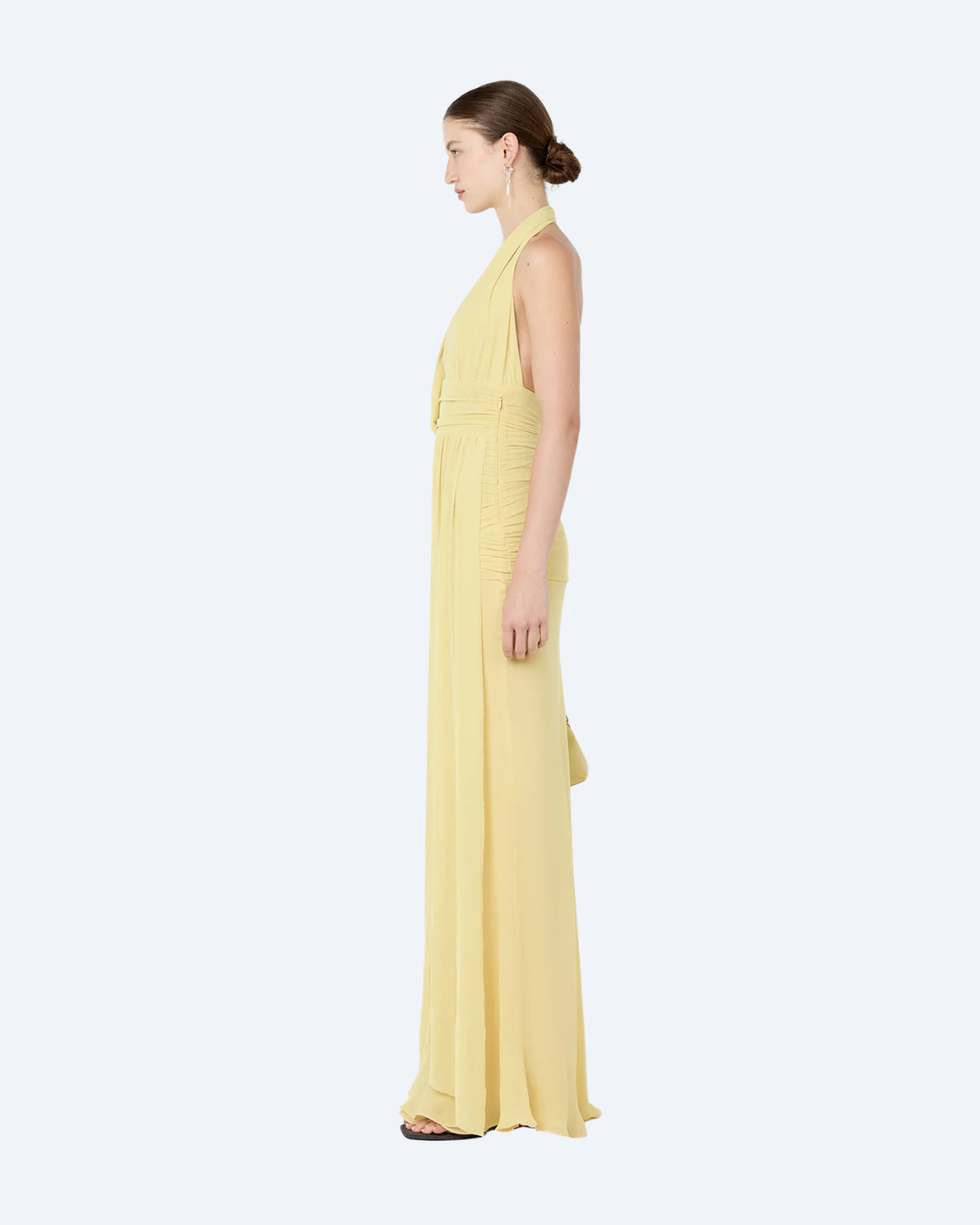 Woman wearing a yellow Bec and Bridge Cassis drape maxi dress, side view, on a white background