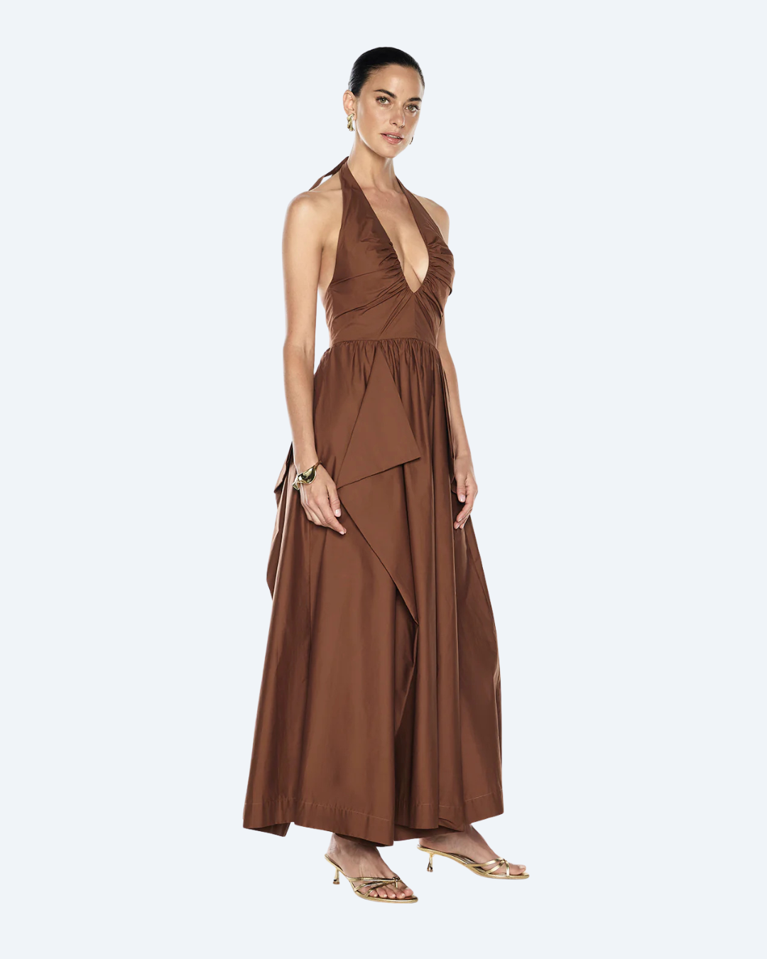 Woman wearing a cognac Manning Cartell Provence halter dress, side view, on a white background.