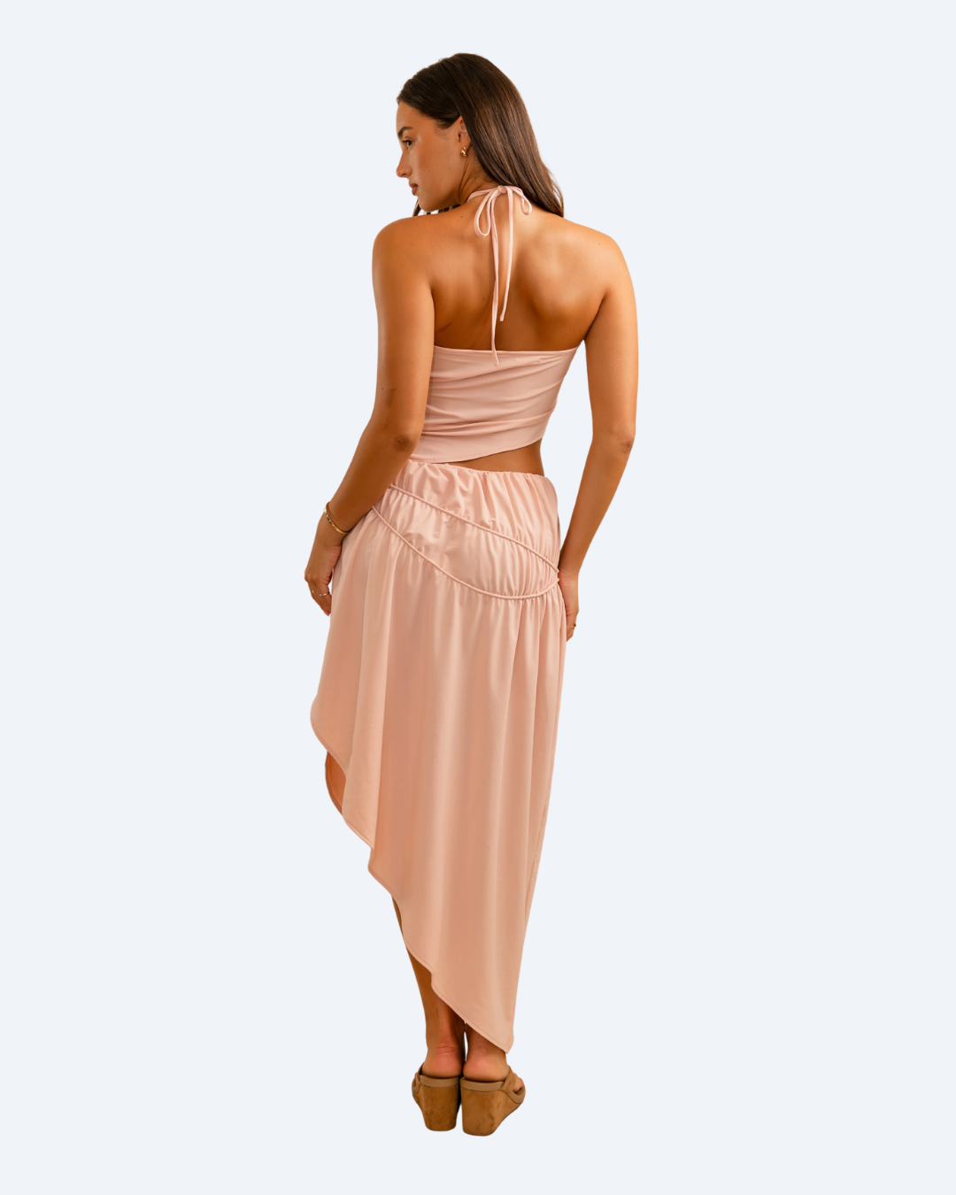 Woman wearing Koster Kulture pink fleur top and skirt set on light gray background, stylish two-piece outfit. back view.