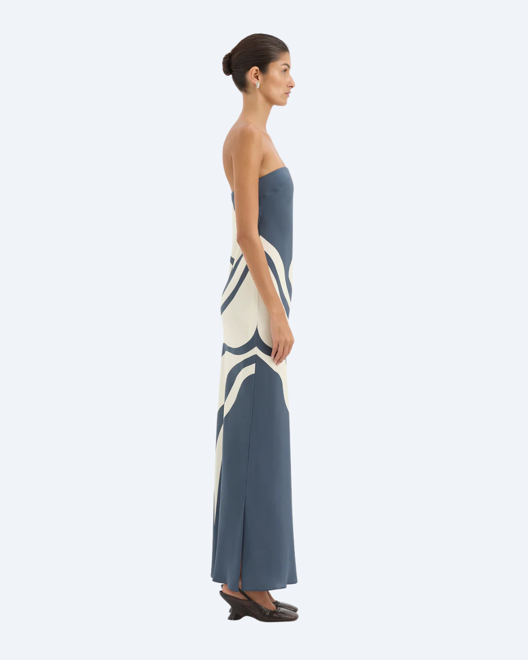 Woman wearing Sir the Label Lilou strapless dress with abstract pattern, side view, on a white background